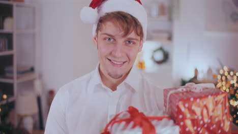 Handsome-man-smiling-while-looking-at-Christmas-gifts-at-home