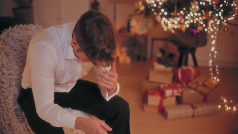Deprimierter-Mann-Mit-Kopf-In-Den-Händen,-Der-Während-Weihnachten-Auf-Einem-Stuhl-Sitzt