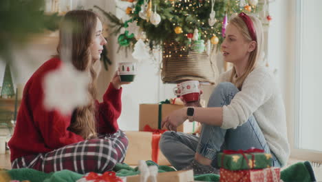 Junge-Schwestern-Diskutieren,-Während-Sie-Zu-Weihnachten-Zu-Hause-Kaffeetassen-In-Der-Hand-Halten