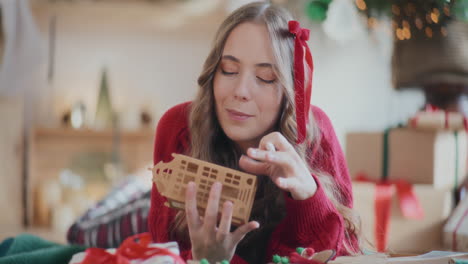 Woman-coloring-cardboard-house-ornament-while-lying-on-floor-during-Christmas