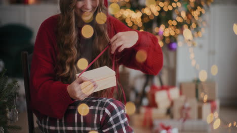 Erstaunte-Frau,-Die-Zu-Weihnachten-Zu-Hause-Eine-Beleuchtete-Geschenkbox-Aus-Holz-öffnet