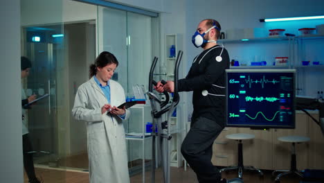 Sportsman-with-mask-running-on-cross-trainer-in-sports-science-laboratory