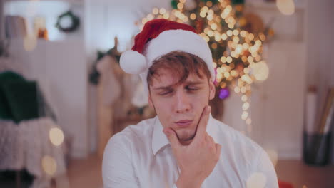 Thoughtful-man-with-hand-on-chin-wearing-Santa-hat-at-home