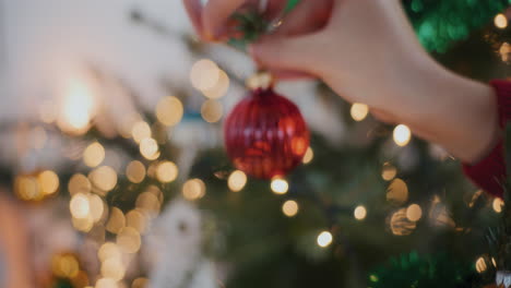 Mujer-Recortada-Decorando-Un-árbol-De-Navidad-Iluminado-Con-Adornos-En-Casa