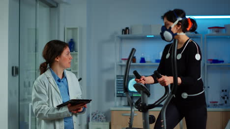 Woman-with-mask-running-on-cross-trainer-testing-heart-rate