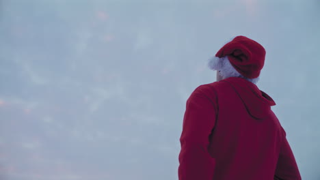 Nachdenklicher-Mann-In-Roter-Kapuzenjacke-Und-Weihnachtsmütze,-Der-Während-Der-Weihnachtszeit-In-Den-Himmel-Blickt