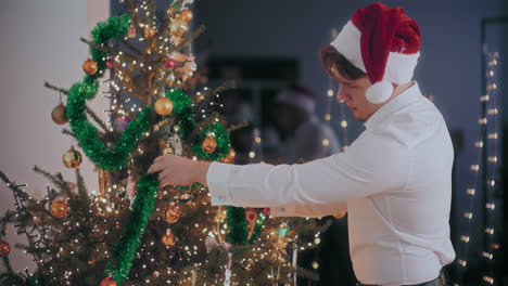 Hombre-Decorando-El-árbol-De-Navidad-Con-Oropeles-Y-Adornos-En-La-Noche
