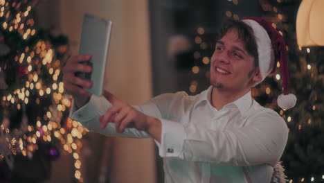 Hombre-Feliz-Tomando-Selfie-A-Través-De-Una-Tableta-Digital-En-Casa-Durante-La-Navidad