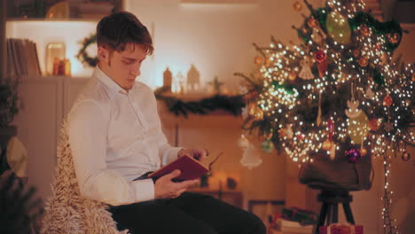 Man-reading-book-while-sitting-on-chair-at-home-during-Christmas