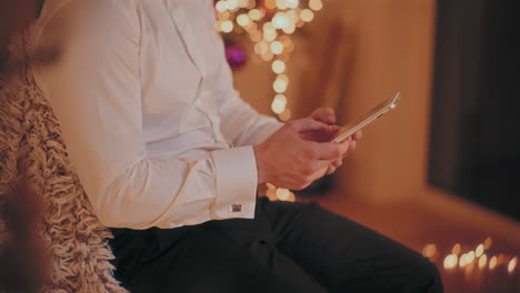 Mann-Benutzt-Digitales-Tablet,-Während-Er-Zu-Weihnachten-Zu-Hause-Auf-Einem-Stuhl-Sitzt
