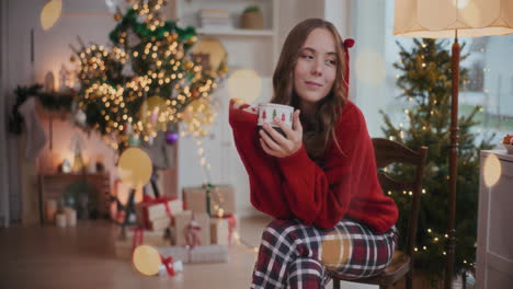 Nachdenkliche-Frau-Hält-Während-Weihnachten-Zu-Hause-Eine-Kaffeetasse-Auf-Einem-Stuhl