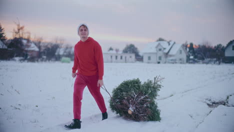 Hombre-Feliz-Tirando-De-Trineo-Con-árbol-De-Navidad-En-Un-Paisaje-Cubierto-De-Nieve