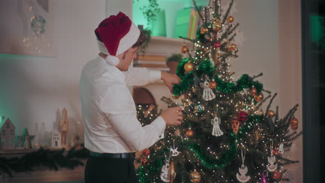 Man-decorating-Christmas-tree-with-tinsels-and-ornaments-at-home