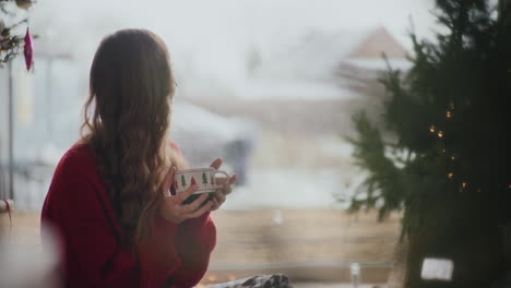 Happy-woman-smelling-fresh-coffee-by-window-during-Christmas