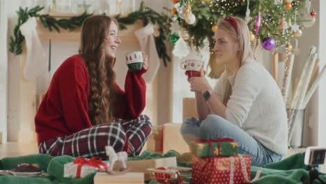 Fröhliche-Schwestern-Reden,-Während-Sie-Zu-Weihnachten-Zu-Hause-Kaffeetassen-In-Der-Hand-Halten