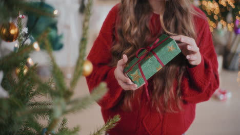 Woman-in-red-sweater-holding-Christmas-present-at-home