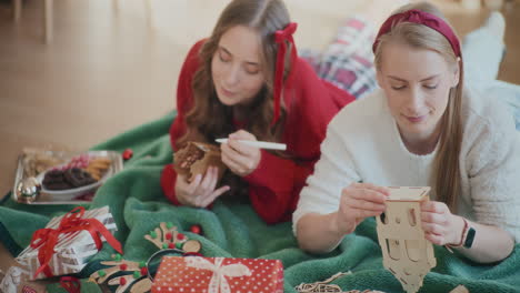 Young-sisters-making-cardboard-house-ornaments-during-Christmas-at-home