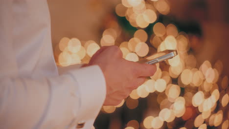 Mann-Benutzt-Mobiltelefon-In-Beleuchtetem-Haus-Während-Weihnachten