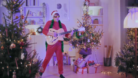 Young-man-playing-guitar-in-decorated-home-during-Christmas