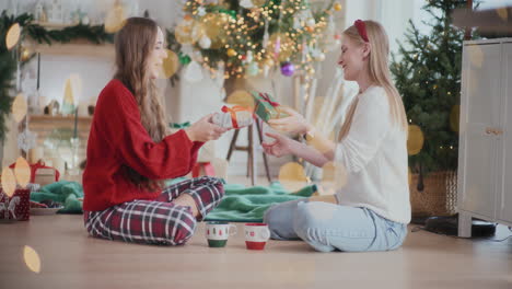Begeisterte-Schwestern-Tauschen-Weihnachtsgeschenke-Auf-Dem-Boden-Zu-Hause-Aus