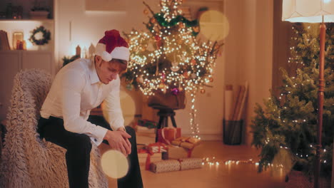 Sad-man-sitting-on-chair-at-illuminated-home-during-Christmas