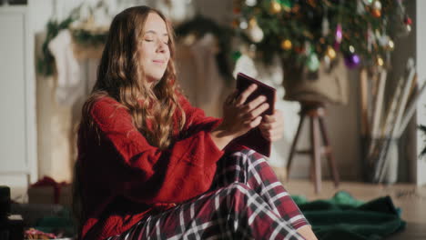Woman-reading-book-and-sitting-with-eyes-closed-at-bright-home-during-Christmas