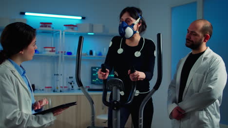 Woman-athlete-with-mask-doing-fitness-exercises-in-science-sport-lab