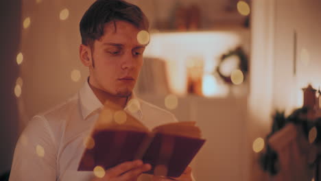 Man-reading-book-while-sitting-at-home-during-Christmas