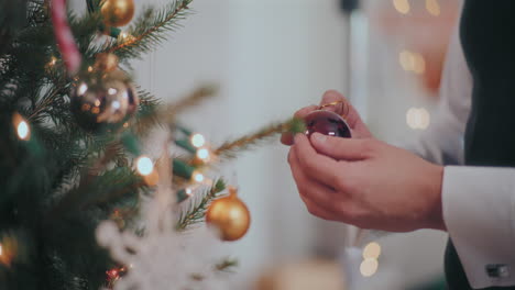 Man-holding-red-glass-bauble-by-Christmas-tree