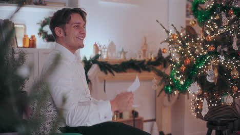 Happy-man-reading-letter-at-decorated-home-during-Christmas