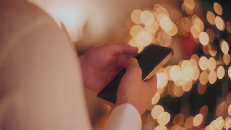 Hand-Mit-Smartphone-Zu-Hause-Während-Weihnachten