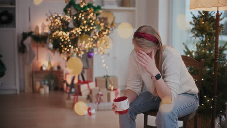 Exhausted-woman-holding-coffee-cup-on-chair-during-Christmas