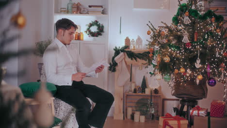Man-reading-letter-at-decorated-home-during-Christmas