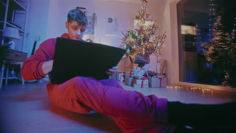Young-man-working-on-laptop-at-home-during-Christmas