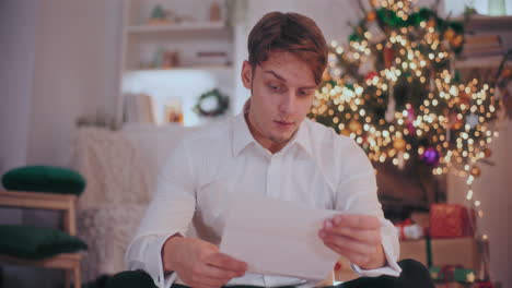 Tensed-man-reading-letter-at-home-during-Christmas
