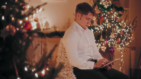 Hombre-Usando-Tableta-Digital-En-Casa-Decorada-Durante-La-Navidad