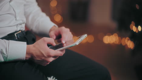 Mann-Nutzt-Zu-Weihnachten-Ein-Digitales-Tablet-Im-Beleuchteten-Zuhause
