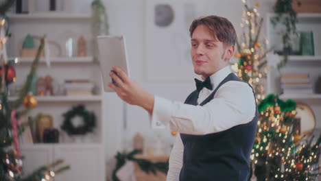 Hombre-Saludando-En-Videollamada-A-Través-De-Una-Tableta-Digital-En-Casa-Durante-La-Navidad