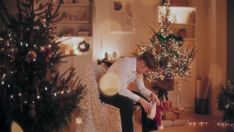 Upset-man-sitting-on-chair-at-illuminated-home-during-Christmas