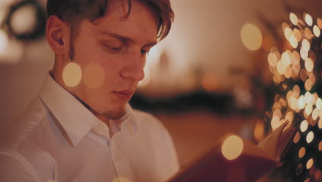 Man-reading-novel-in-illuminated-home-during-Christmas