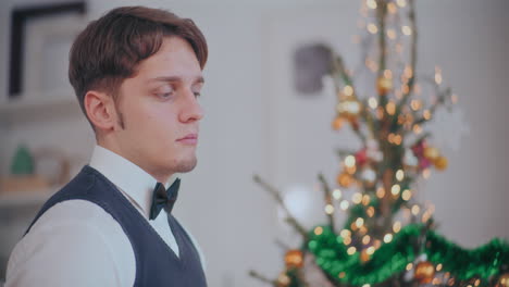 Thoughtful-man-with-decorated-Christmas-tree-in-background-at-home