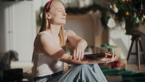 Woman-with-eyes-closed-holding-book-at-bright-home-during-Christmas