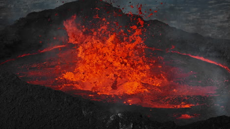 Close-up-view-of-boiling-lava-lake-inside-volcano-crater,-drone-top-down-shot