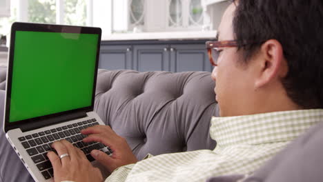 Hombre-Asiático-Usando-Una-Computadora-Portátil-De-Pantalla-Verde-En-Casa-Filmada-En-R3d