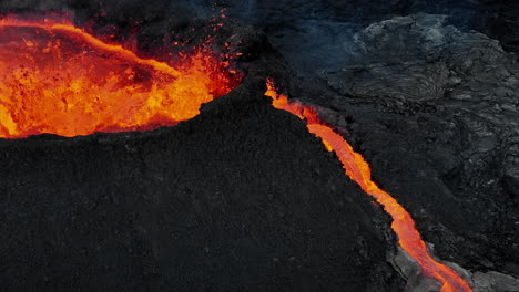 Erupting-volcano,-magma-splashing-out-a-crater-making-lava-flows,-drone-close-up