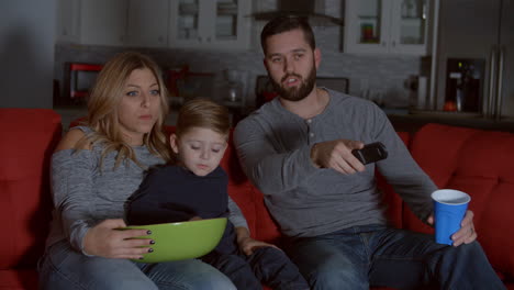Slow-Motion-Shot-Of-Family-Sitting-On-Sofa-Watching-TV