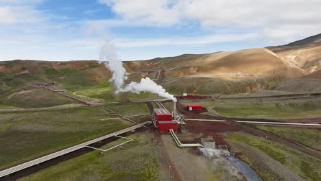 Geothermal-power-station-in-Icelandic-landscape,-steaming-chimneys-in-a-valley