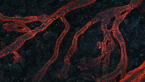 Streams-of-red-hot-lava-flowing-during-a-volcano-eruption,-aerial-shot