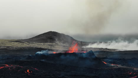 Apocalyptic-surroundings-of-an-erupted-volcano,-lava-and-smoke-spreading,-aerial