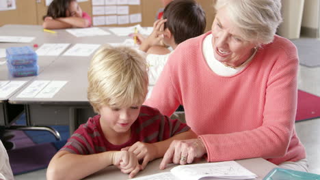 Senior-teacher-helps-young-schoolboy-in-class,-elevated-view